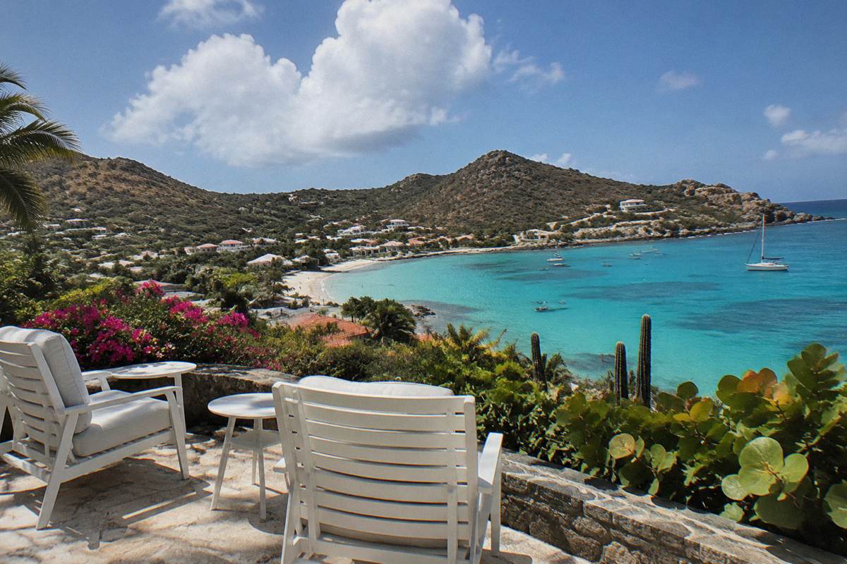 A quiet hotel terrace with white chairs overlooking a Caribbean bay