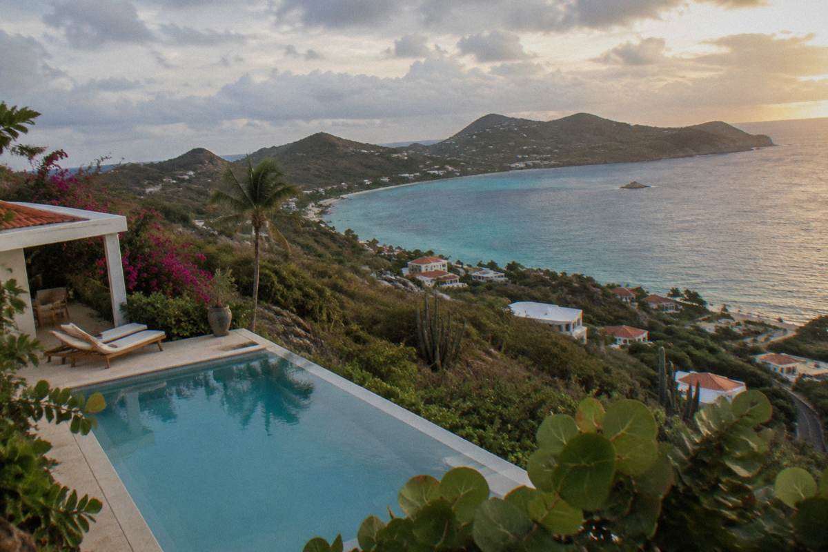 A hillside villa with a private pool overlooking a Caribbean bay at golden hour