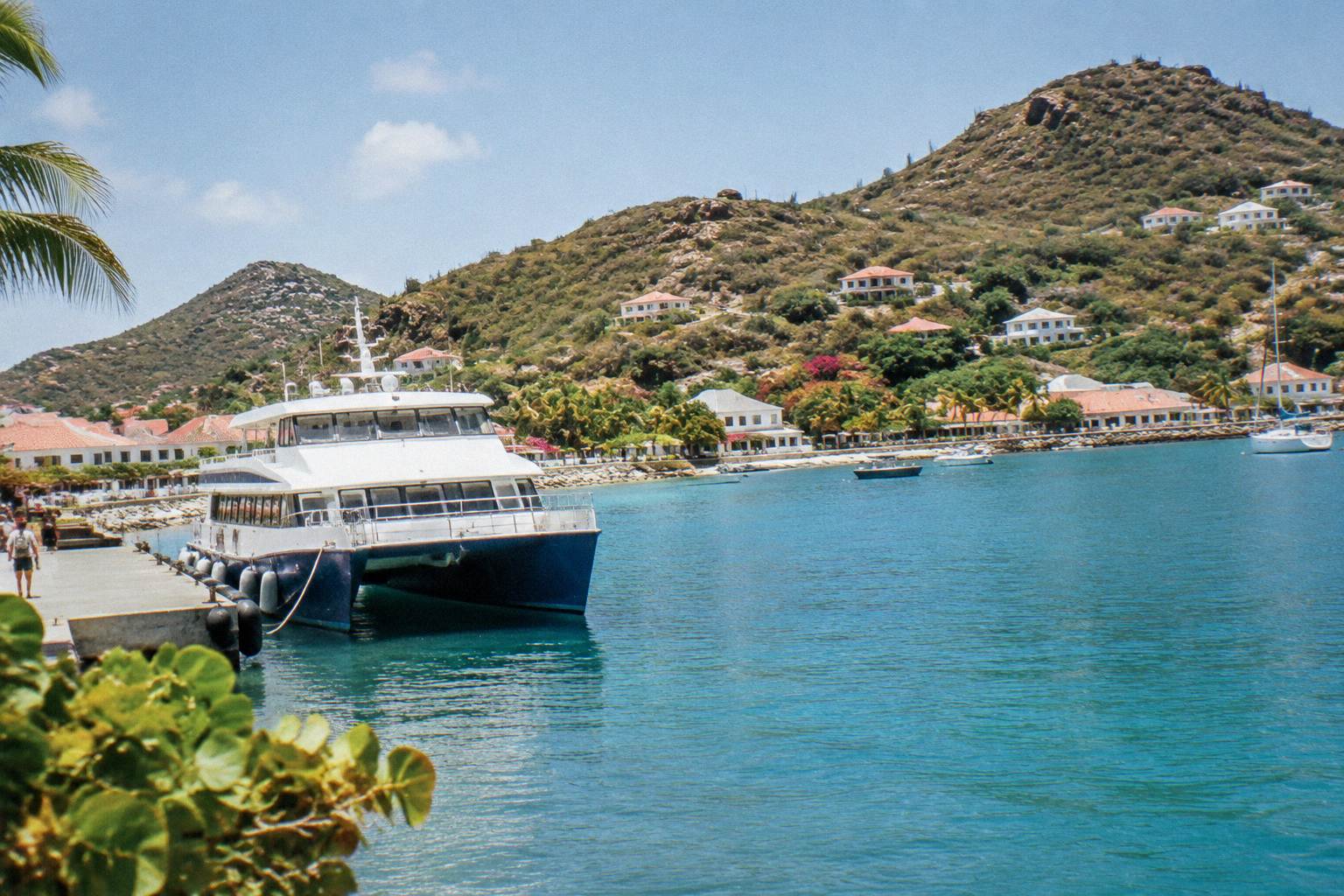 A passenger ferry moored at a Caribbean harbour with hills behind
