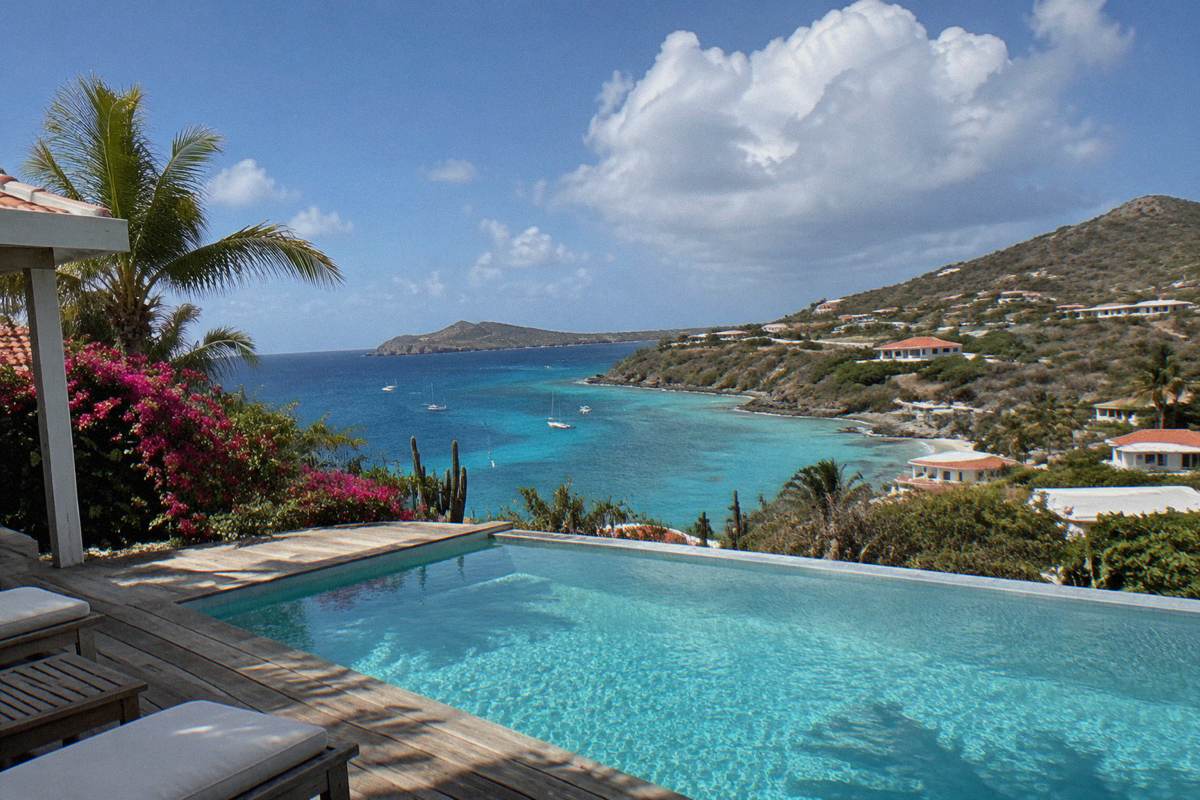 Private villa pool terrace facing the sea with wooden decking and no people