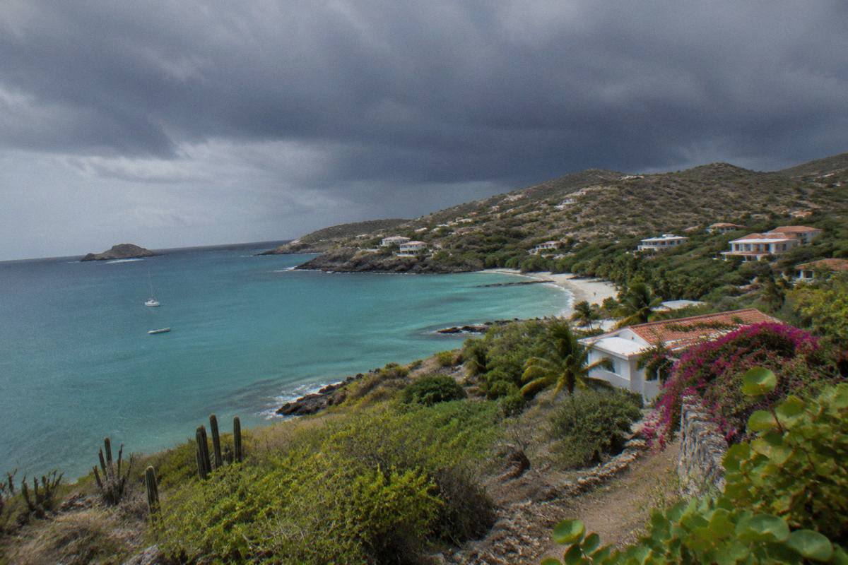 Dark storm clouds gathering over turquoise water and a rocky Caribbean coastline
