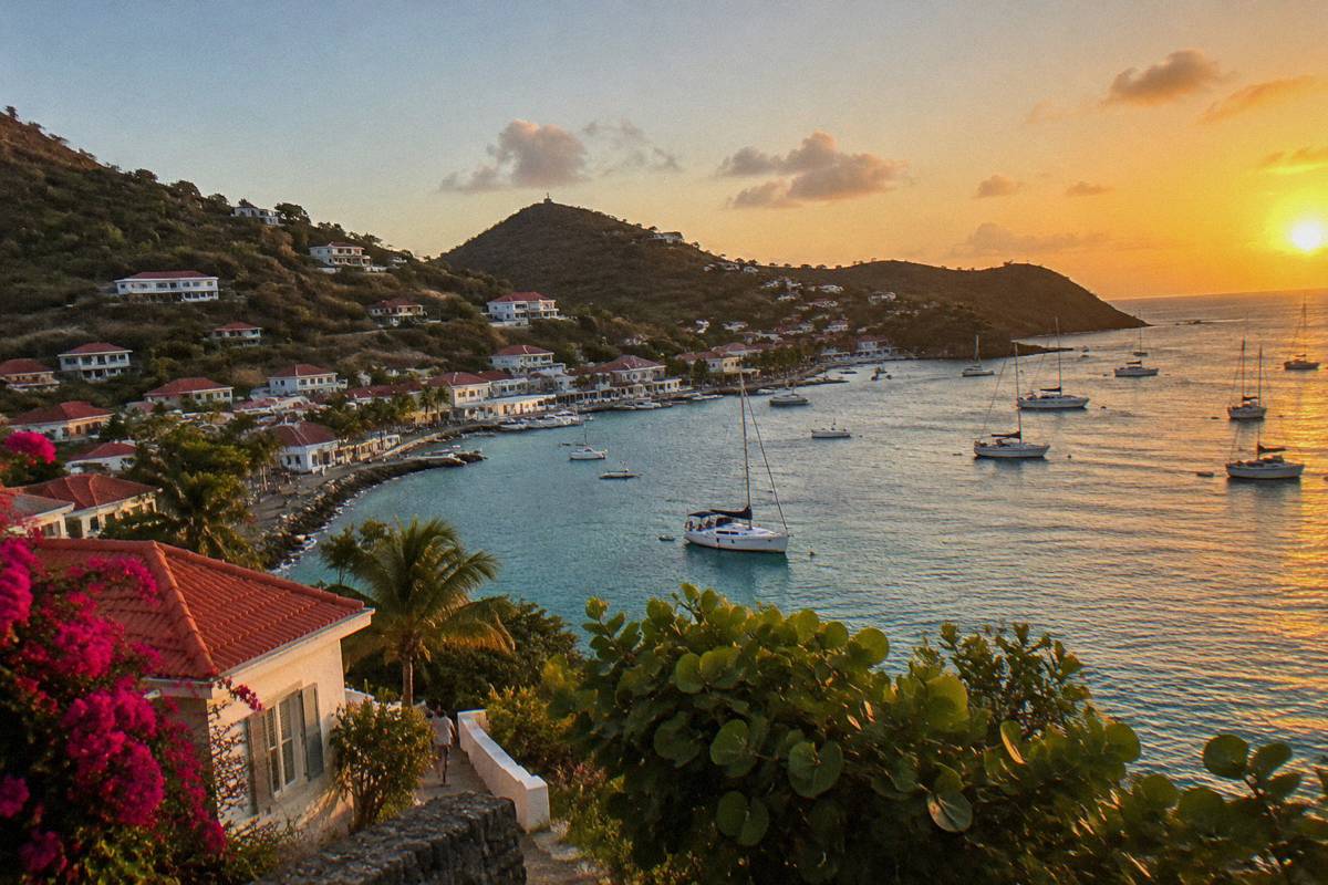 Harbour town with anchored boats and hillsides at sunset in Gustavia