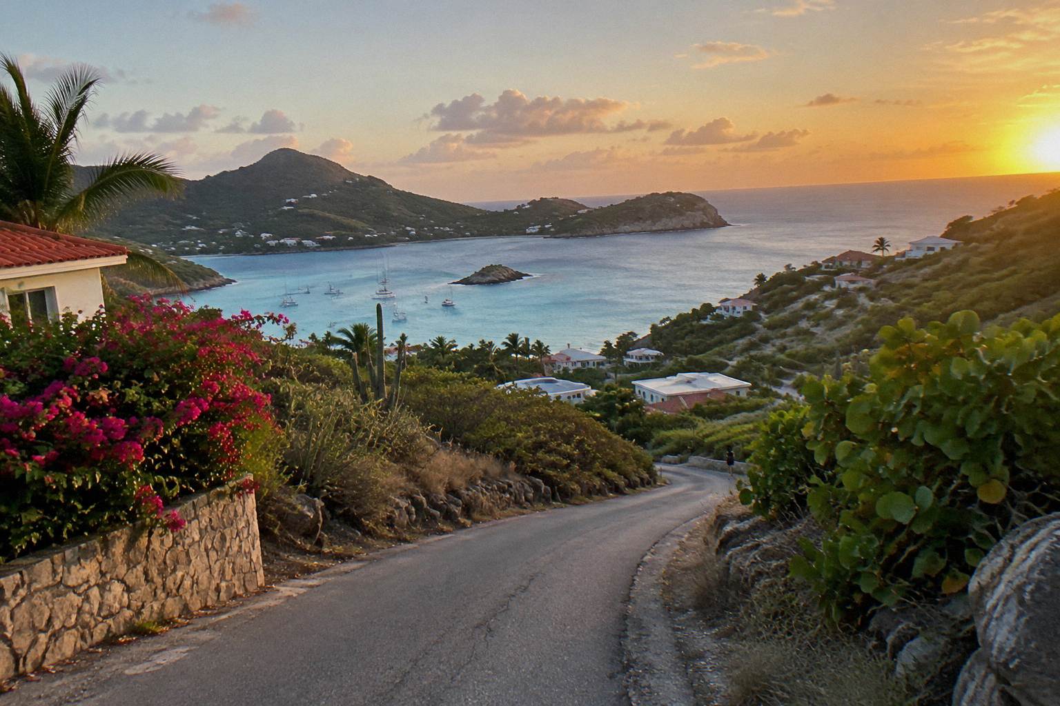 A narrow winding island road curving between low green hills toward a distant bay