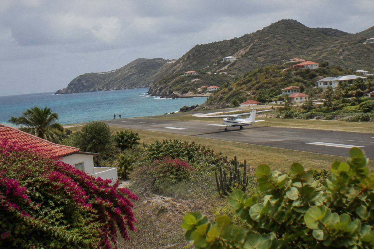Small aircraft on a short Caribbean runway with green hills behind it