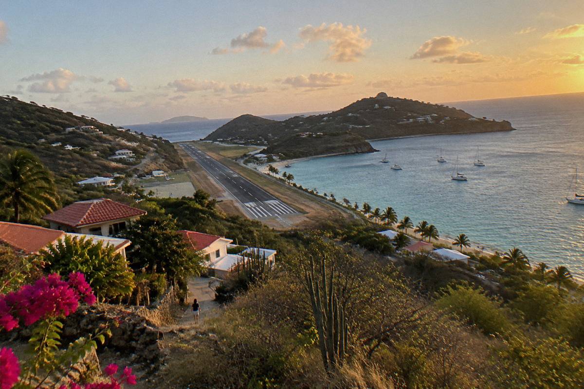 Small aircraft on a short runway between green hills near the sea