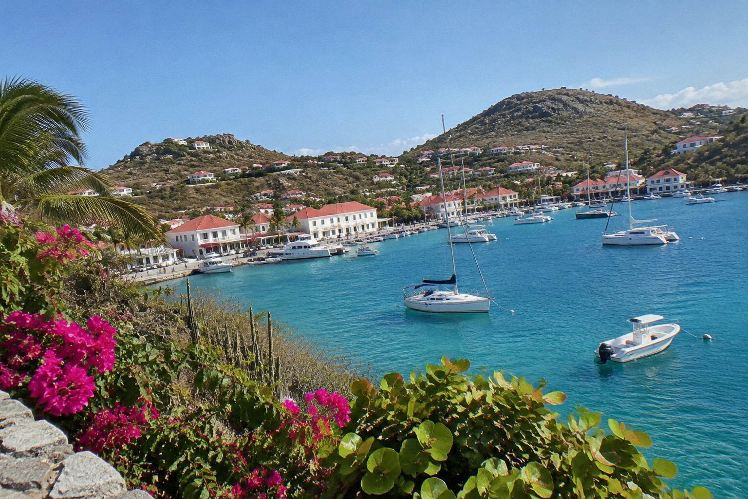 White buildings and boats along the harbour of Gustavia under a clear sky