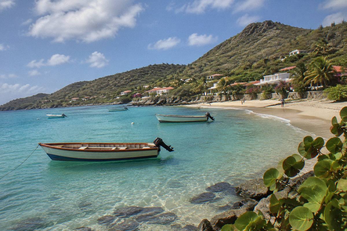 Small wooden boats moored in clear shallow water along a Caribbean beach