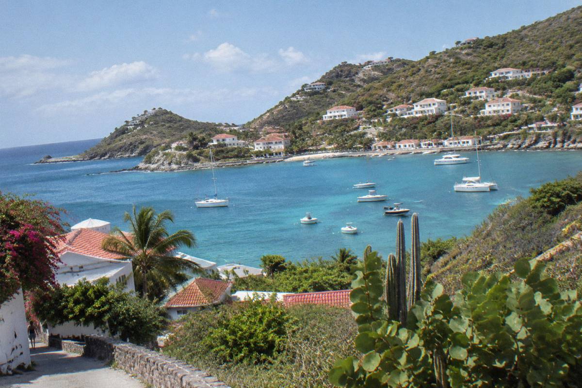 Whitewashed buildings on a green hillside above a small Caribbean harbour