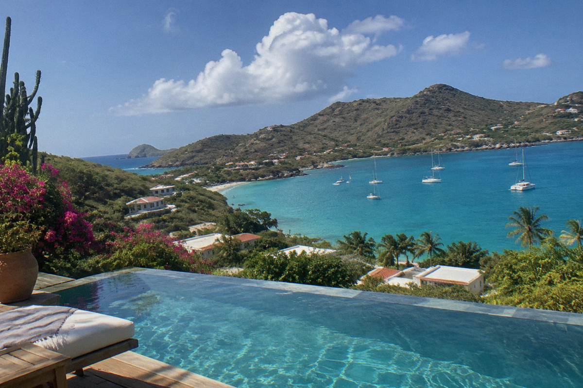 Infinity pool terrace overlooking a calm bay with green hills beyond