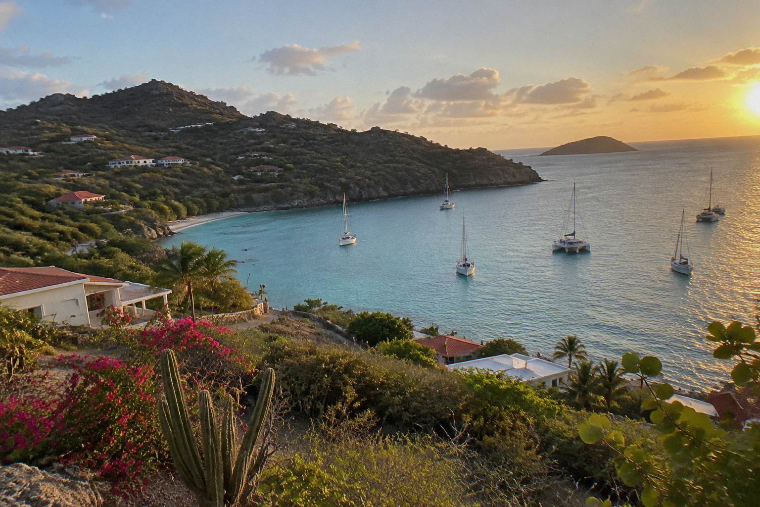 Turquoise bay on Saint Barthelemy with wooded headland and anchored sailboats