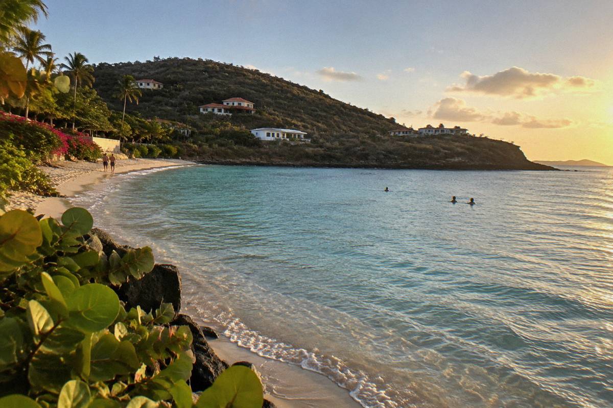 Shallow clear water at a sandy Caribbean bay with a low rocky point in the distance