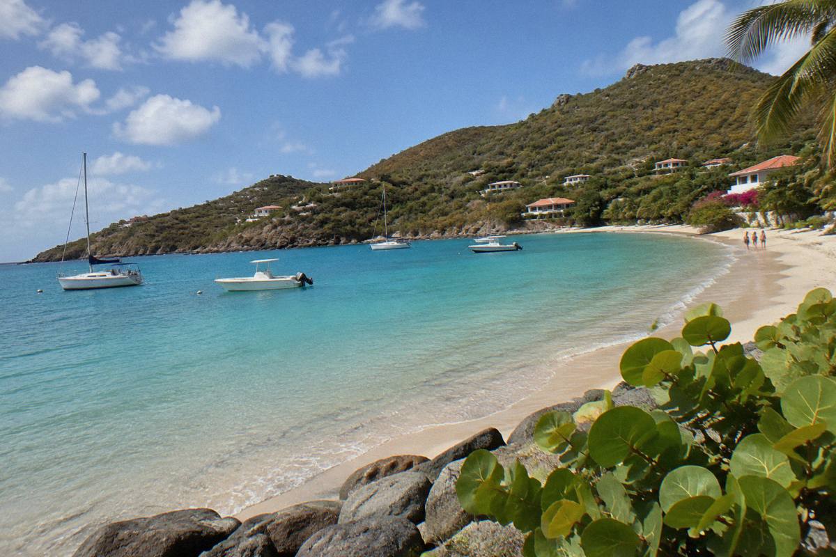 A sheltered sandy beach on Saint Barthelemy with calm shallow water and a few moored boats.