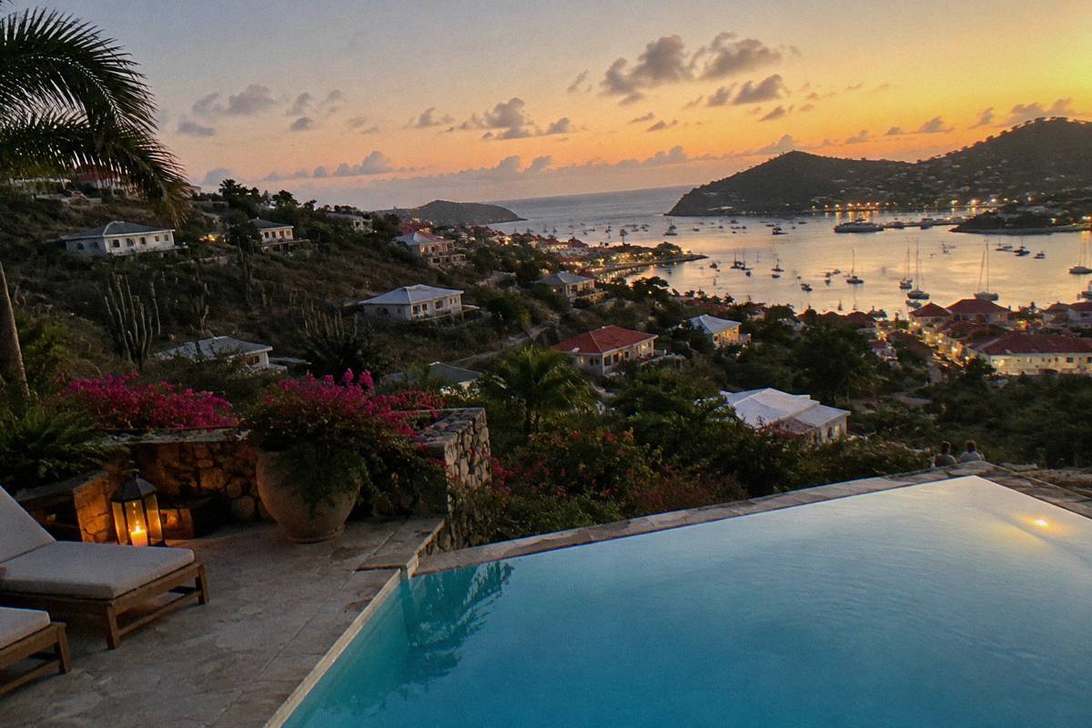 Lit swimming pool terrace above the Gustavia harbour lights at night