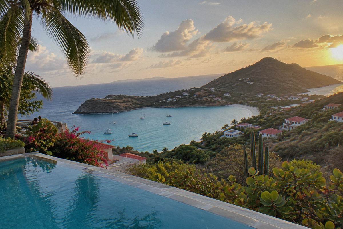 Palm-fringed infinity pool overlooking a calm Caribbean bay at golden hour