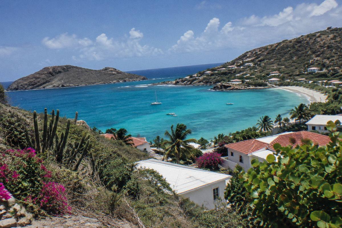 Turquoise bay seen from a hillside above white rooftops