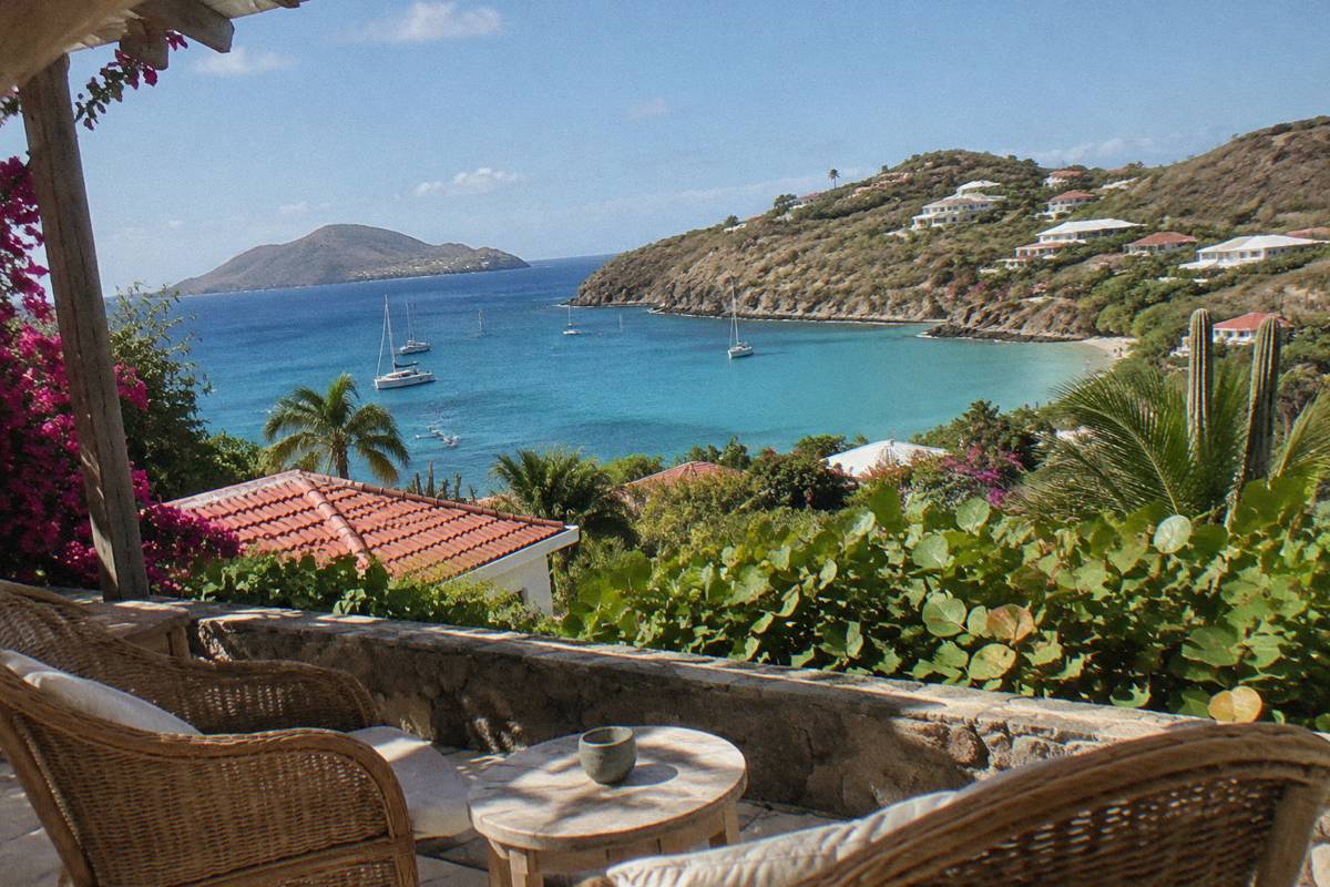 Small inn terrace with rattan chairs facing a calm bay