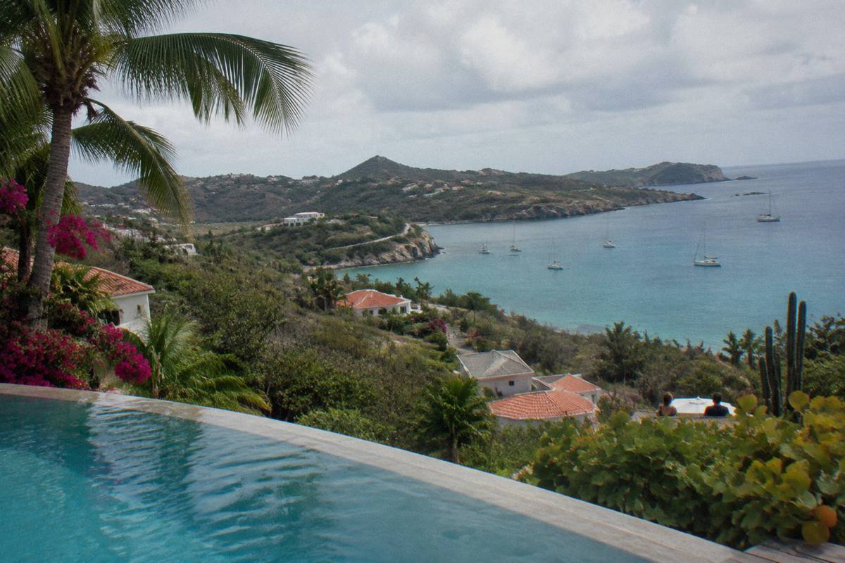 Hotel swimming pool edged with palms looking out over a calm bay