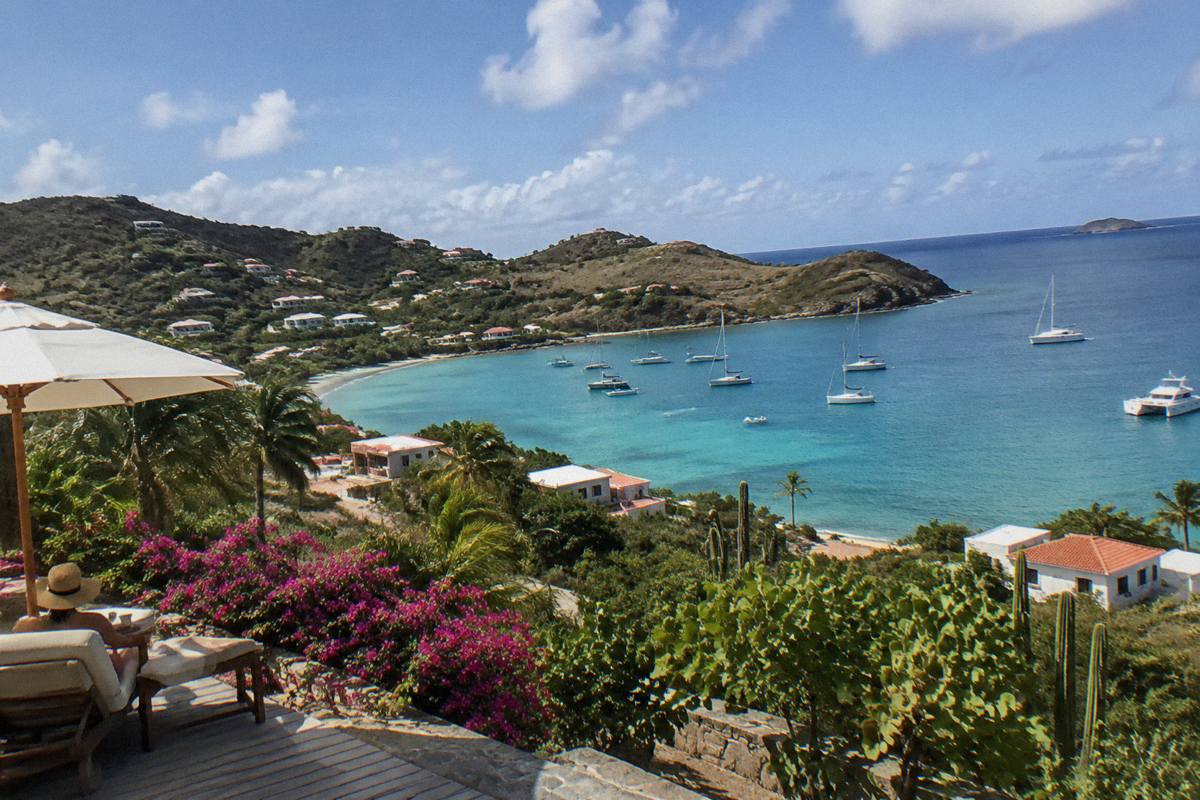 A hillside hotel terrace overlooking a calm bay with moored boats