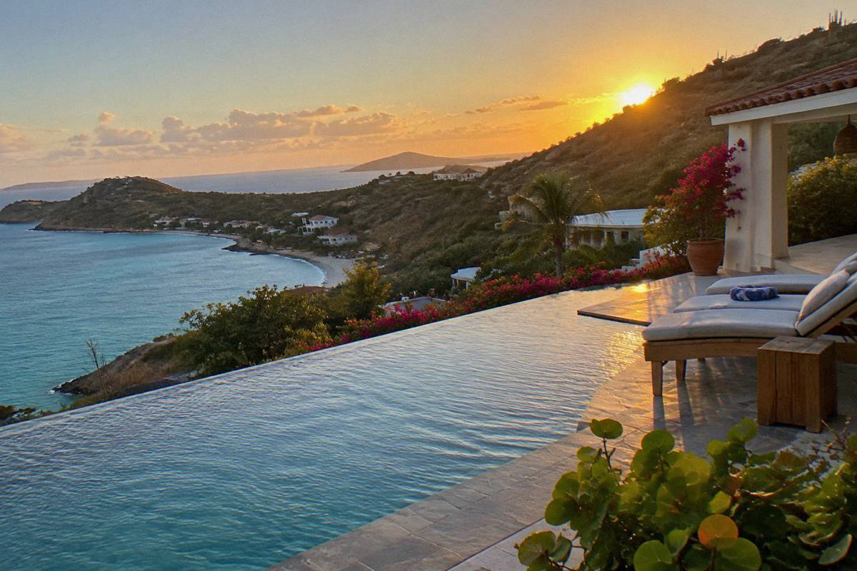 Infinity pool at a Saint Barthelemy villa at sunset with lounge chairs