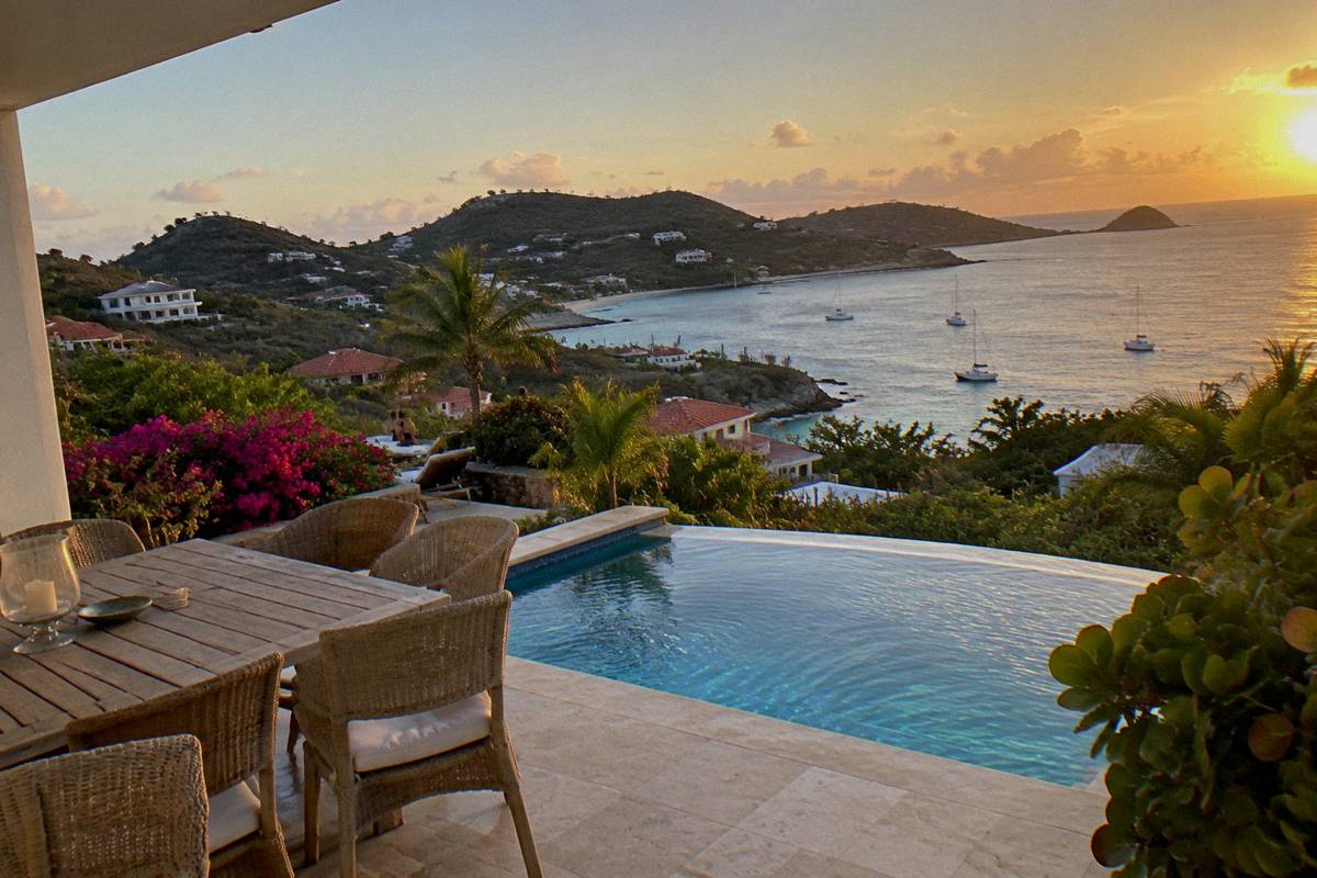 Family villa terrace with dining table and pool looking over the coast