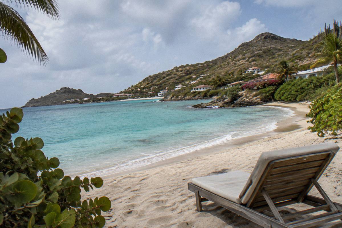 An empty sun lounger on sand under a bright sky
