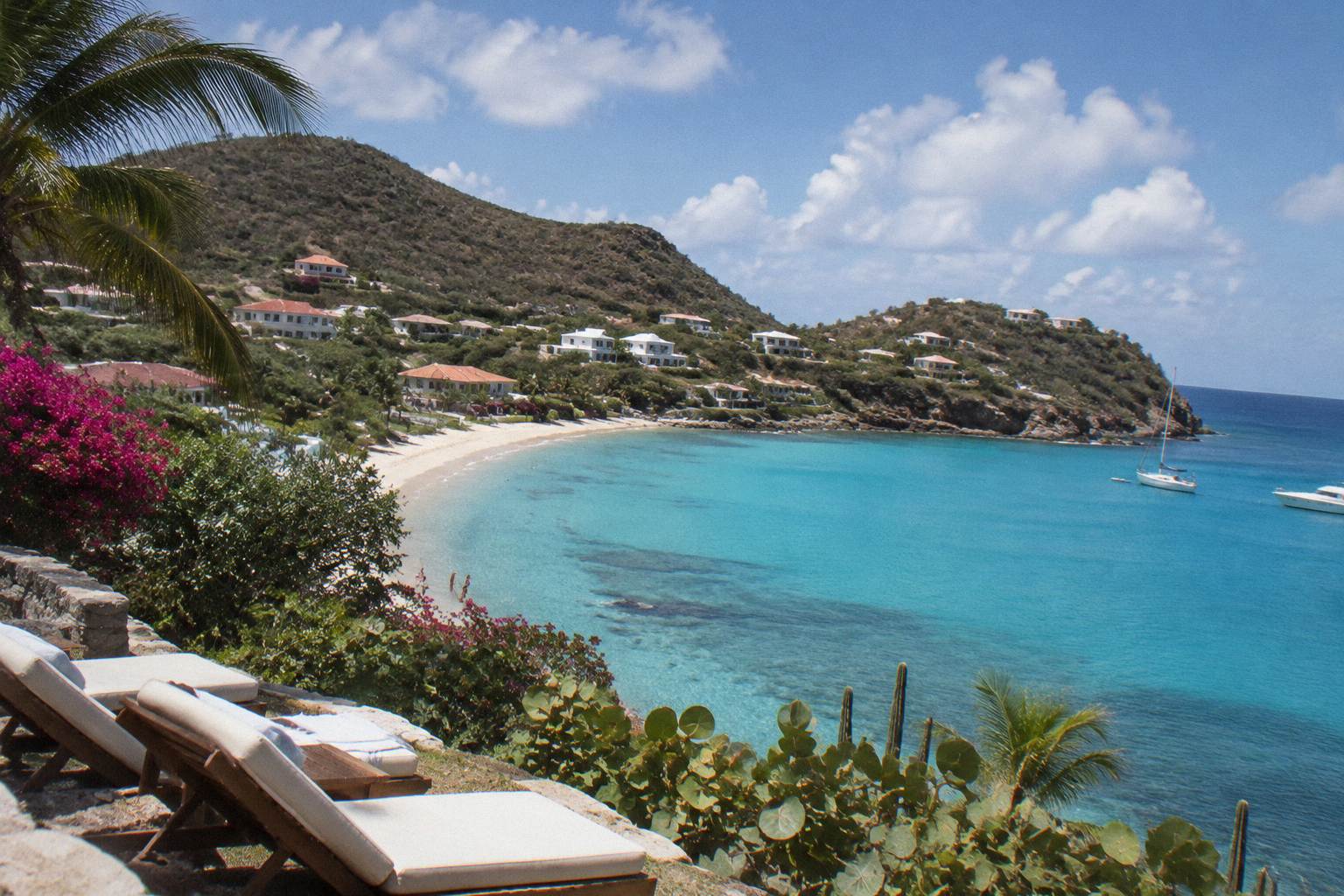 Sun loungers and calm turquoise water along a Caribbean bay