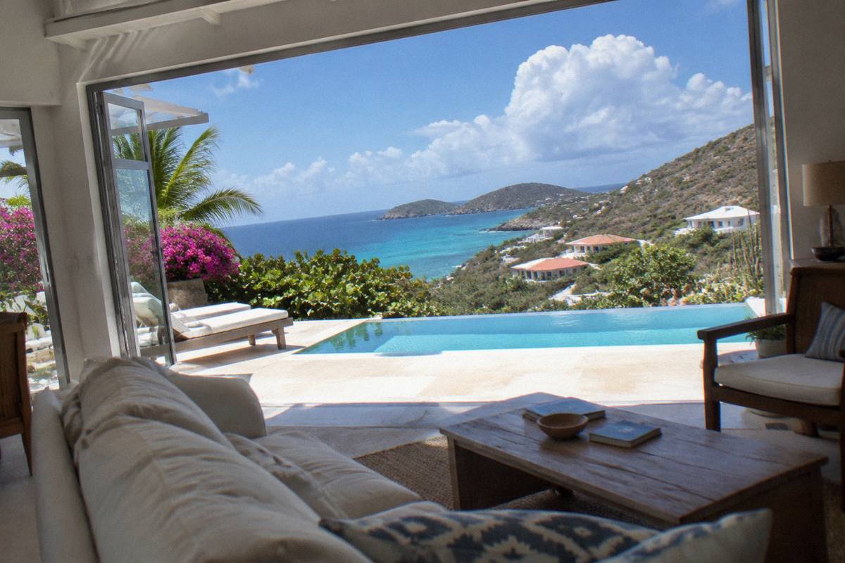 A modern villa living room with open doors leading toward the sea
