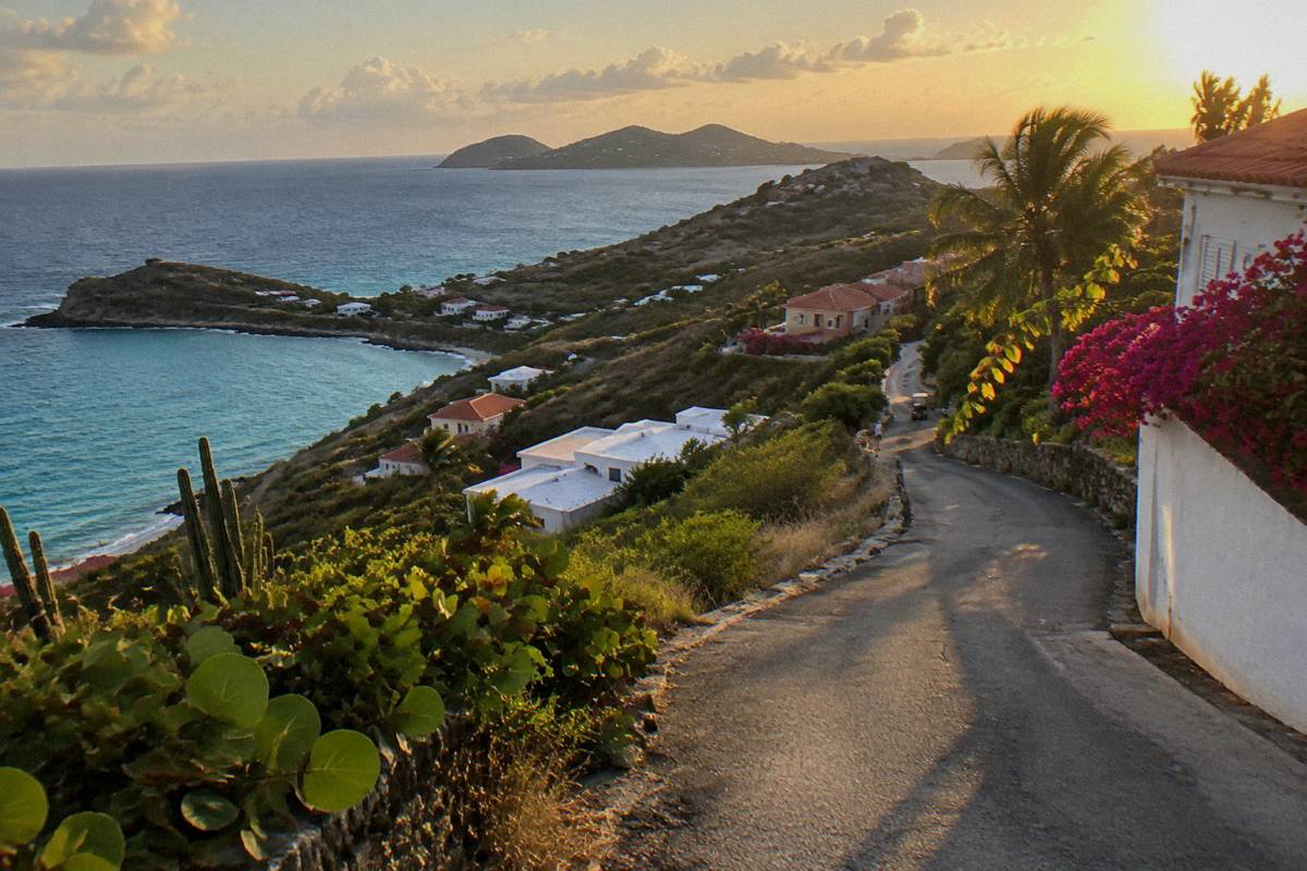 A narrow winding road through green hills above the sea on a small Caribbean island