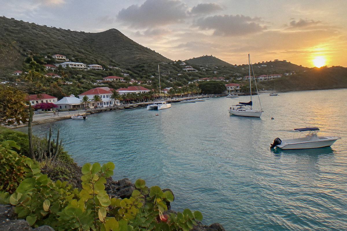 Sunset over a small Caribbean harbour with boats moored near a town waterfront
