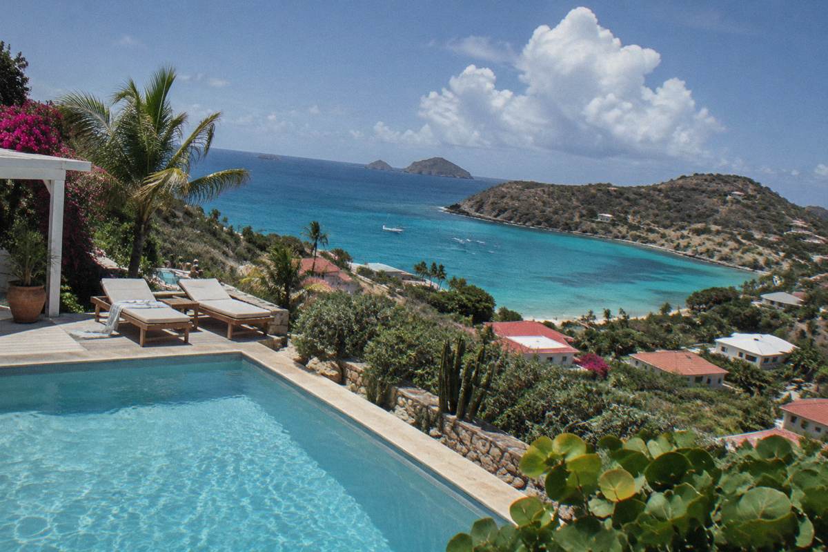 A private villa pool terrace with sun loungers overlooking the sea