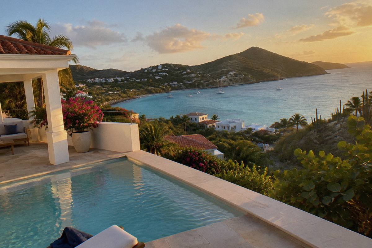 White villa terrace with private swimming pool overlooking a calm bay and green headland