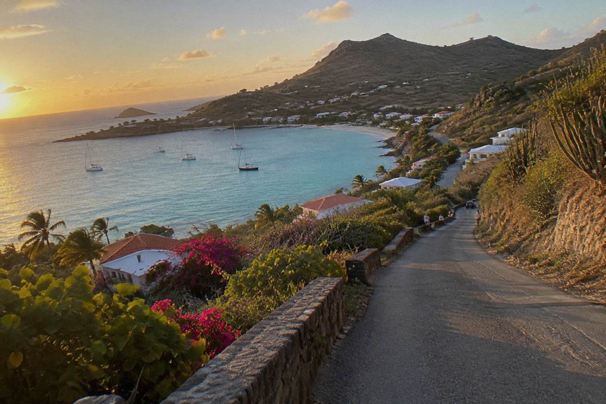 Narrow winding island road with dry hillside vegetation above the coast