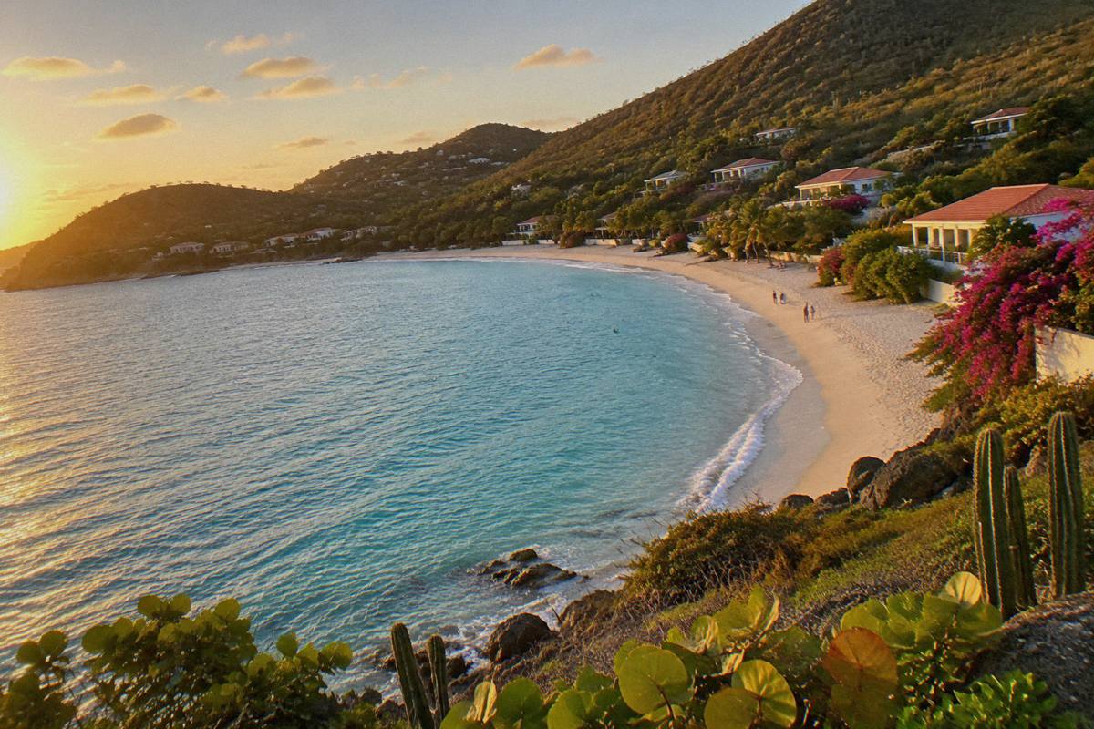 Turquoise water meeting a curved sandy beach with green hills in the background