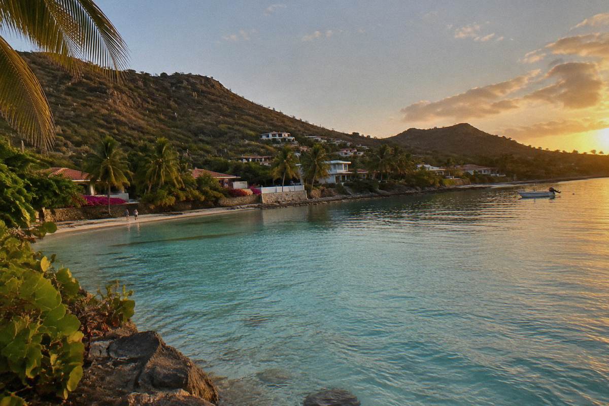 Shallow calm lagoon at Grand Cul-de-Sac with palm trees and waterfront buildings along the shore