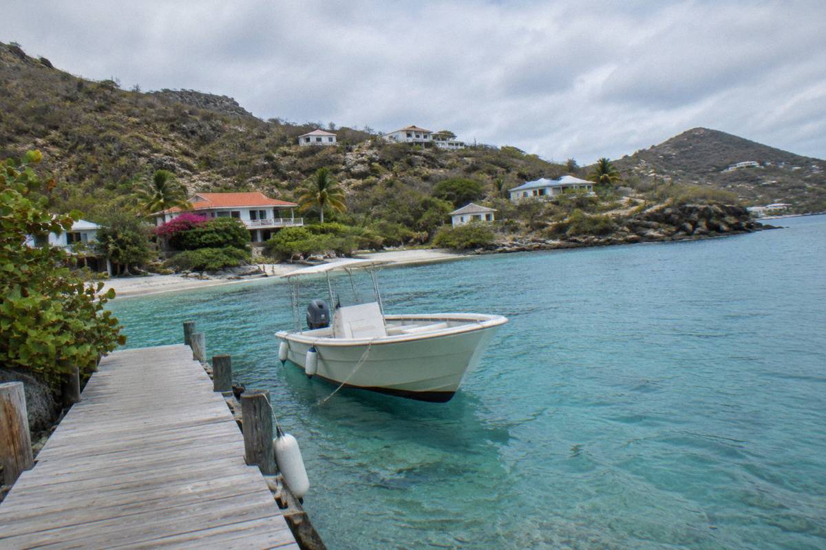 Wooden dock leading into clear shallow water with a moored boat