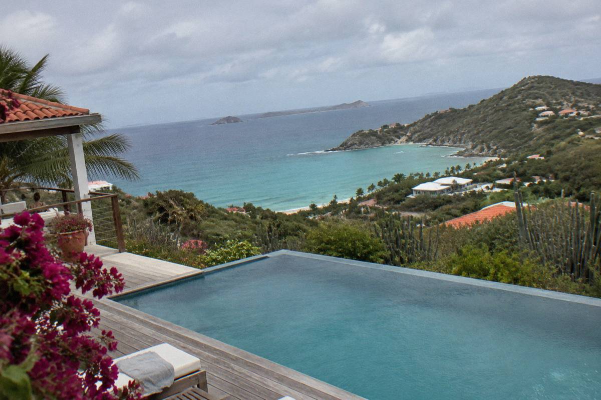 A hillside villa terrace with an infinity pool facing the open Atlantic ocean and green slopes