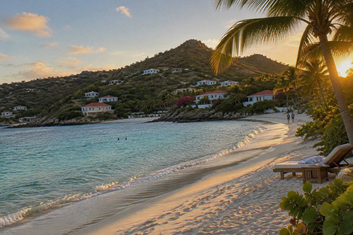 Palm-fringed white sand beach with calm shallow water and a resort sun lounger