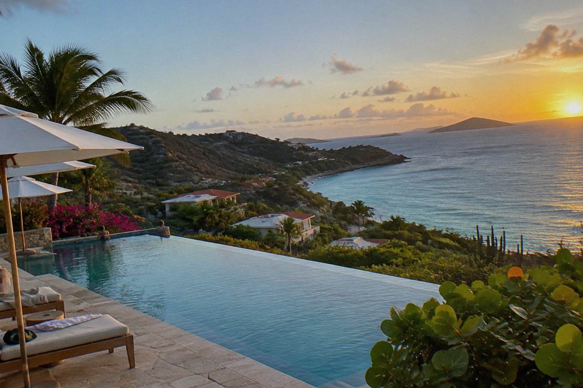 Infinity pool edge meeting the sea at a resort with sun loungers and umbrellas