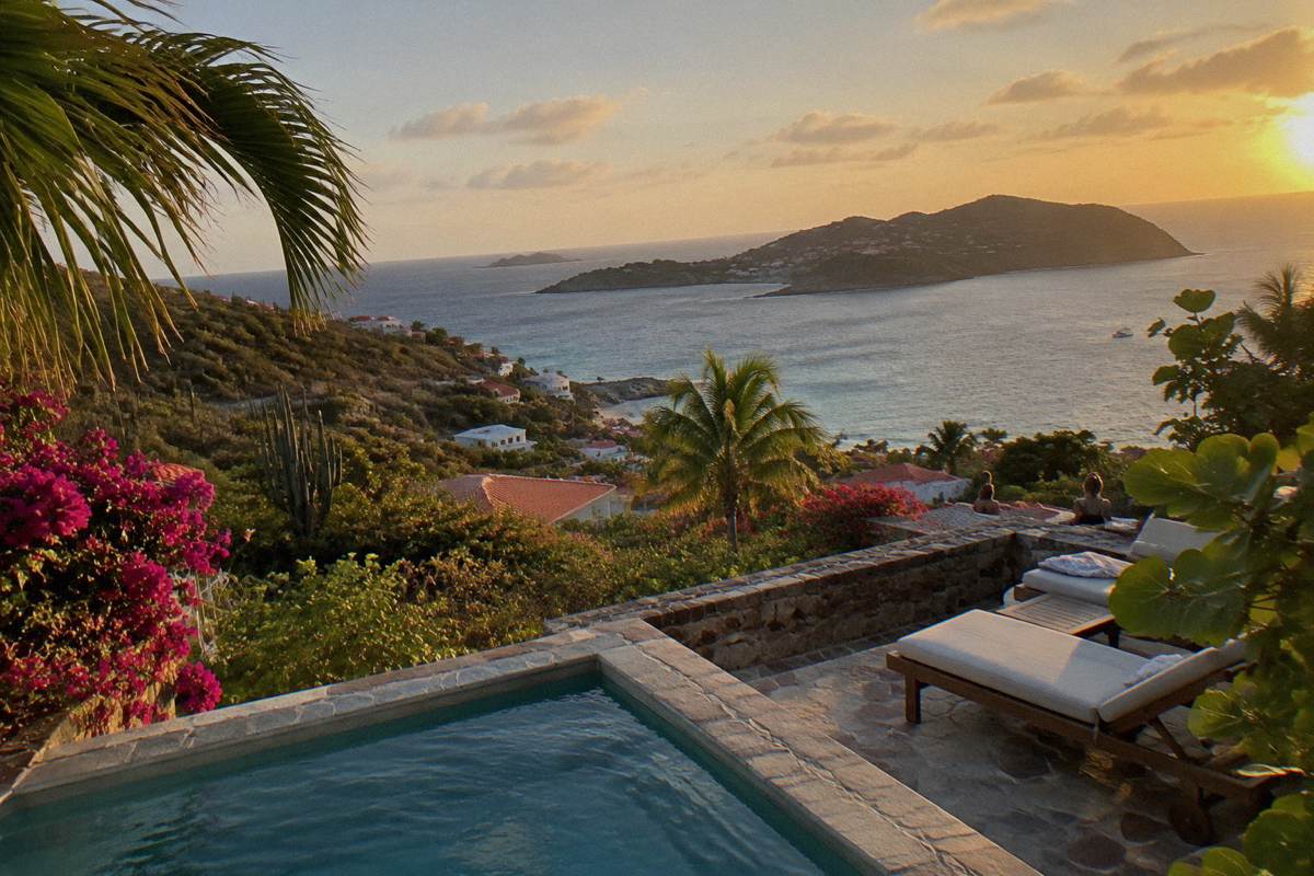 A stone terrace with a small plunge pool, sun loungers and an open sea view between tropical plants