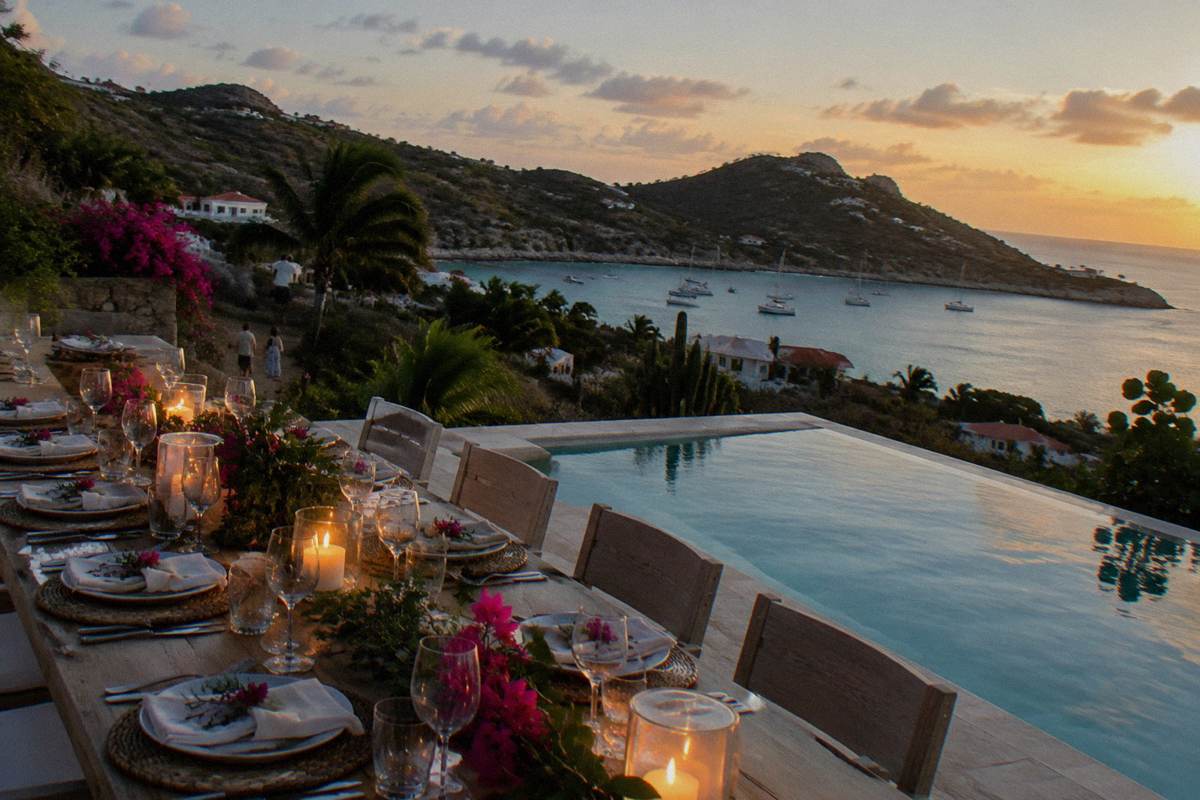 A long dinner table set for a festive meal on a pool terrace at night