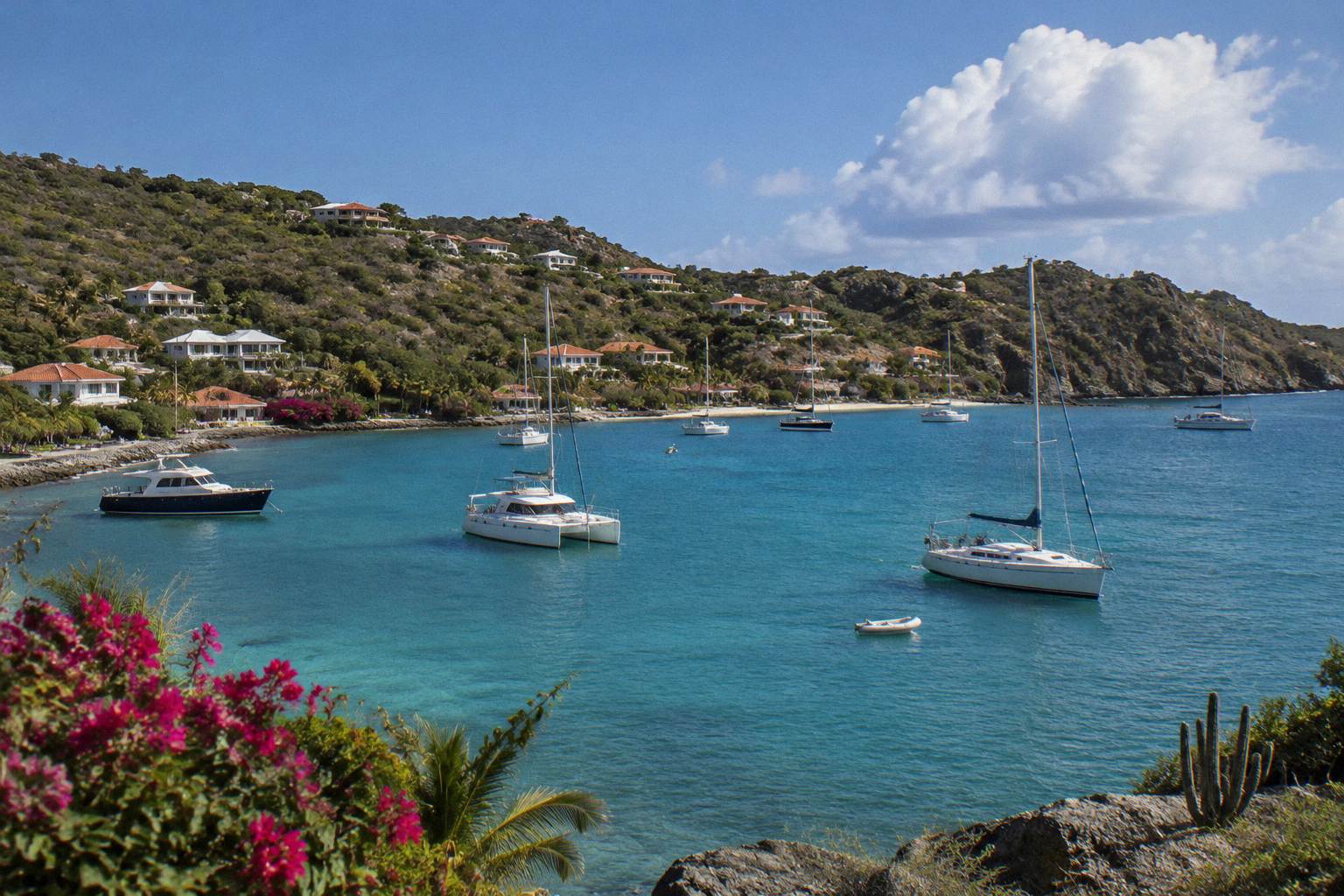 Boats anchored in a harbour at dusk with hillside lights above the water