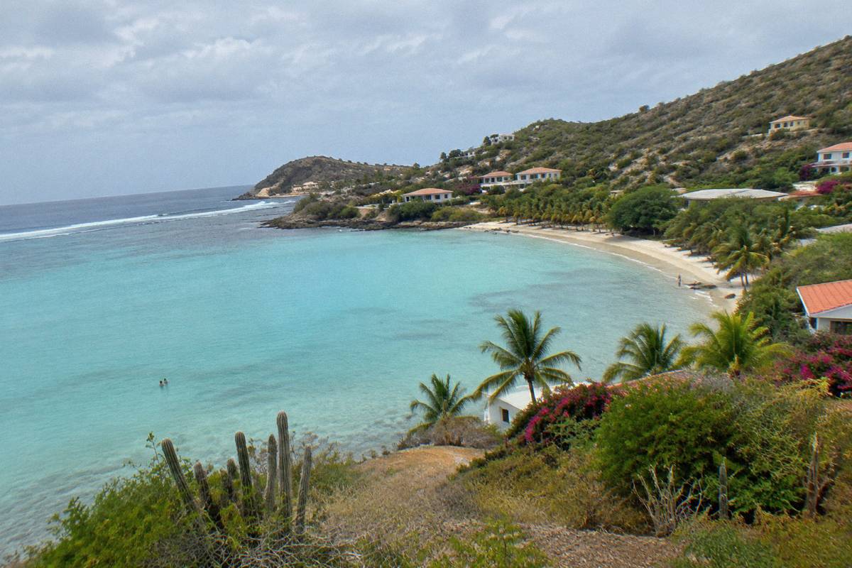 A calm shallow lagoon with turquoise water protected by a reef line and palm trees along the shore