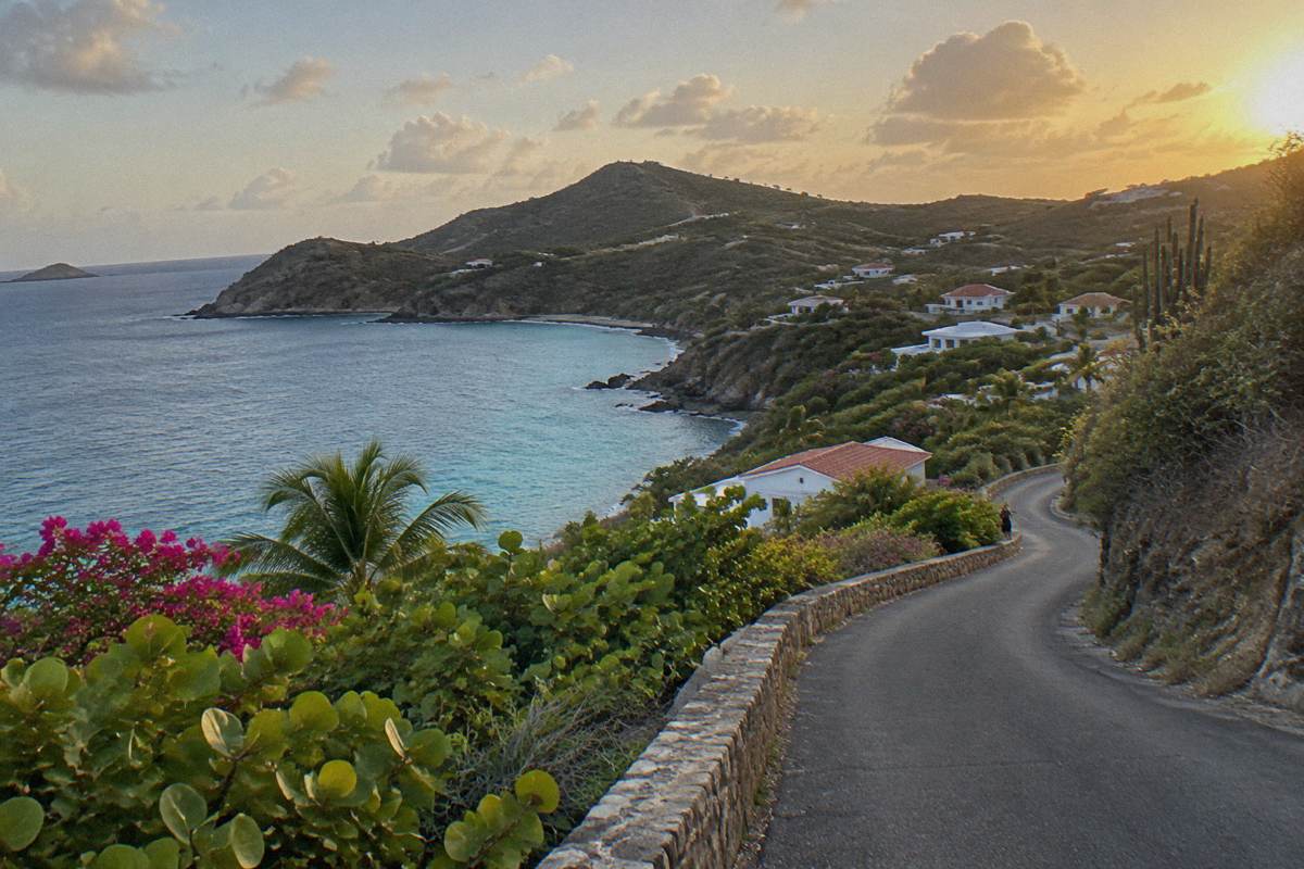 An empty winding island road along a green coastline
