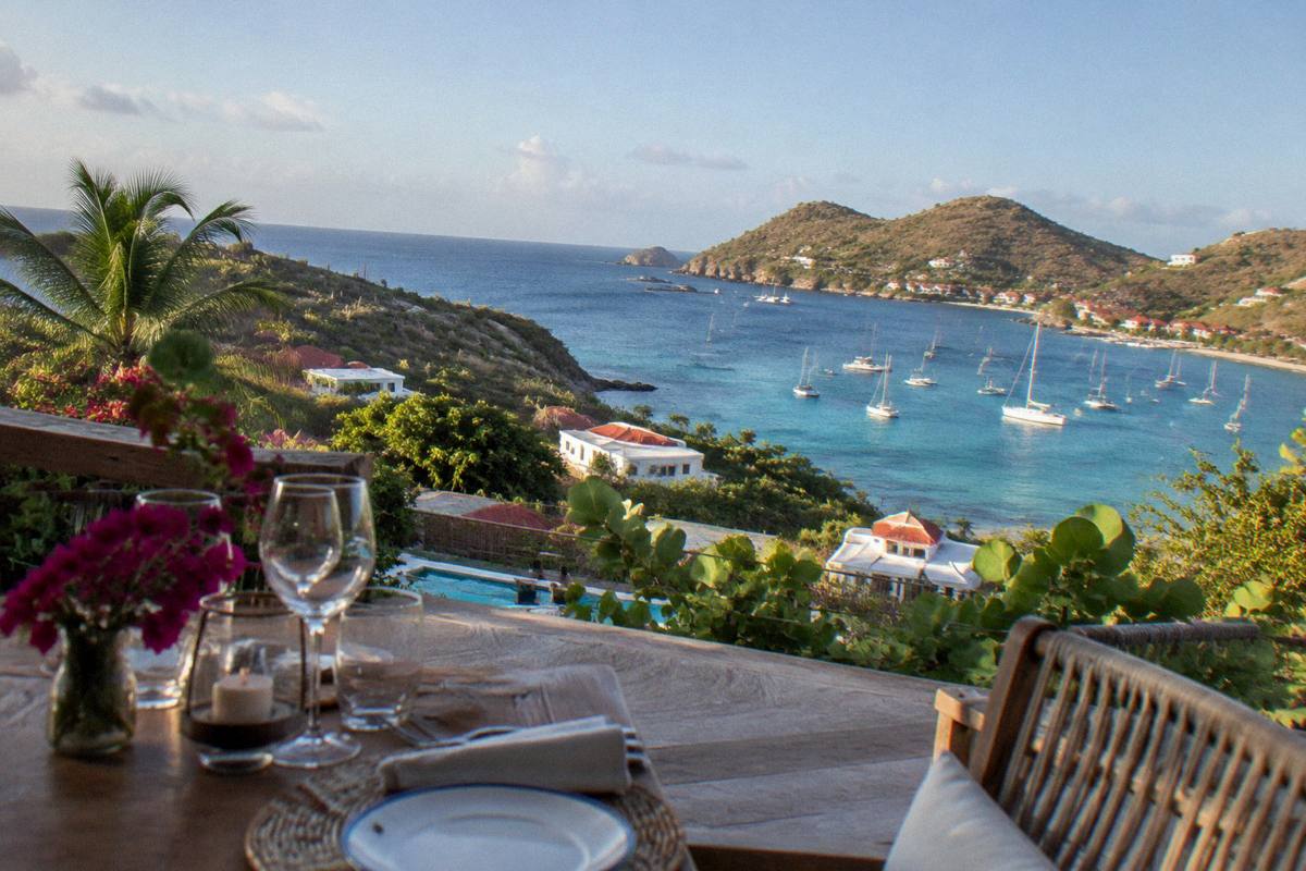 A set dinner table on a terrace overlooking the harbour at dusk