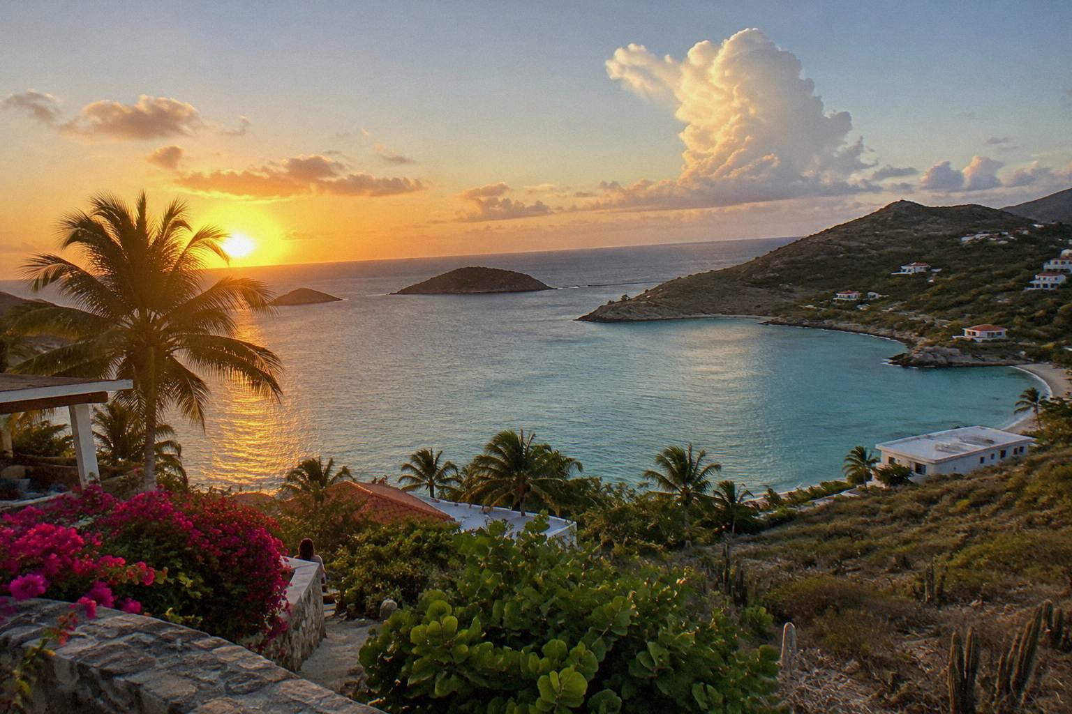 Sunset over a calm Caribbean bay with a hillside terrace and palm trees