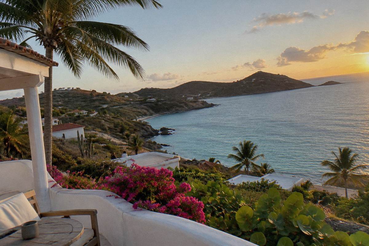 A small whitewashed hotel terrace above the sea with palm trees