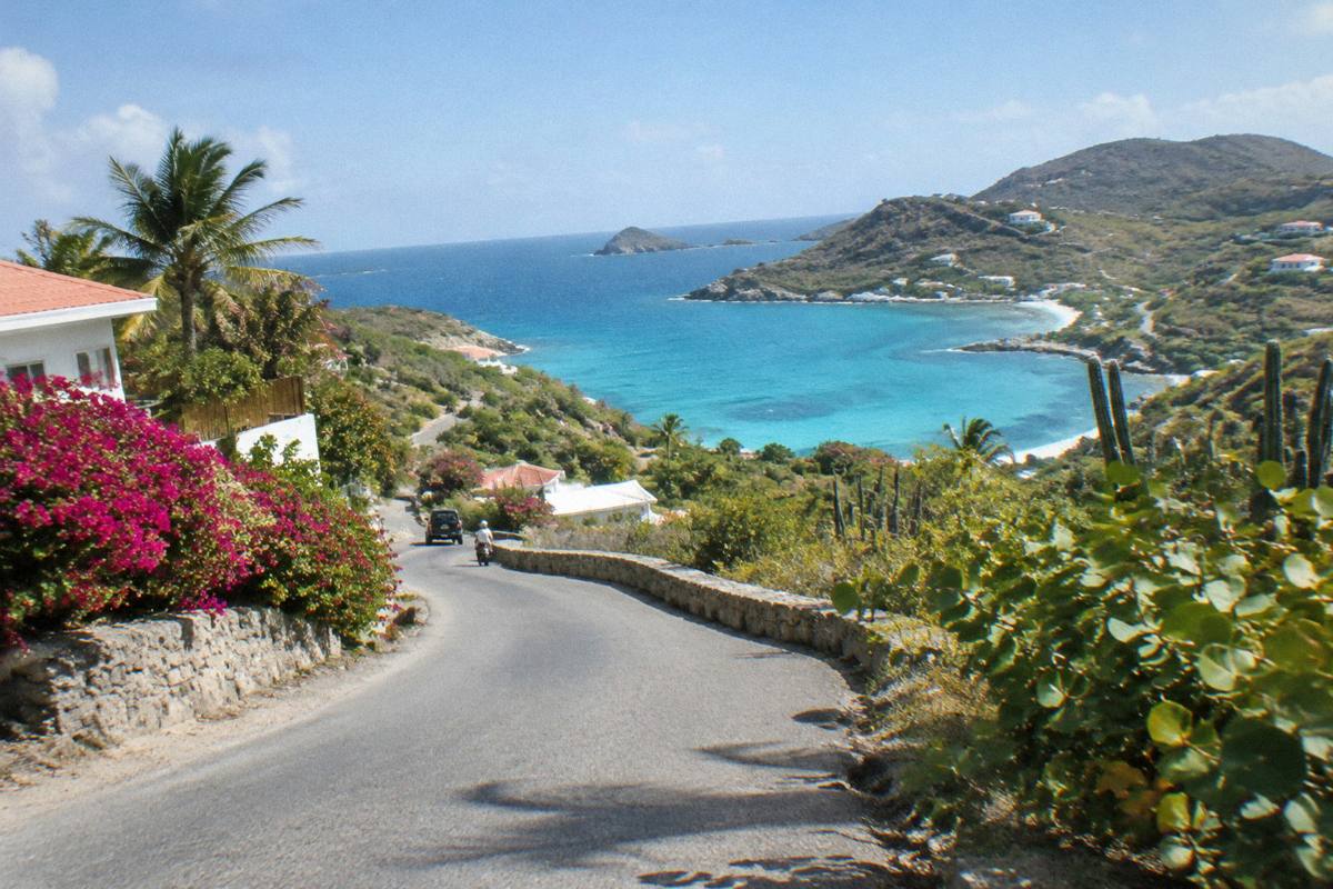 A narrow winding island road with sea views and green hills