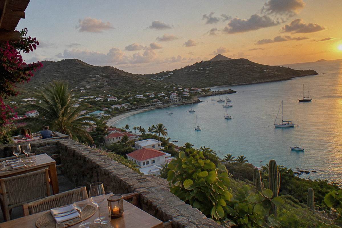 Evening tables set with glasses along a stone terrace above a harbour