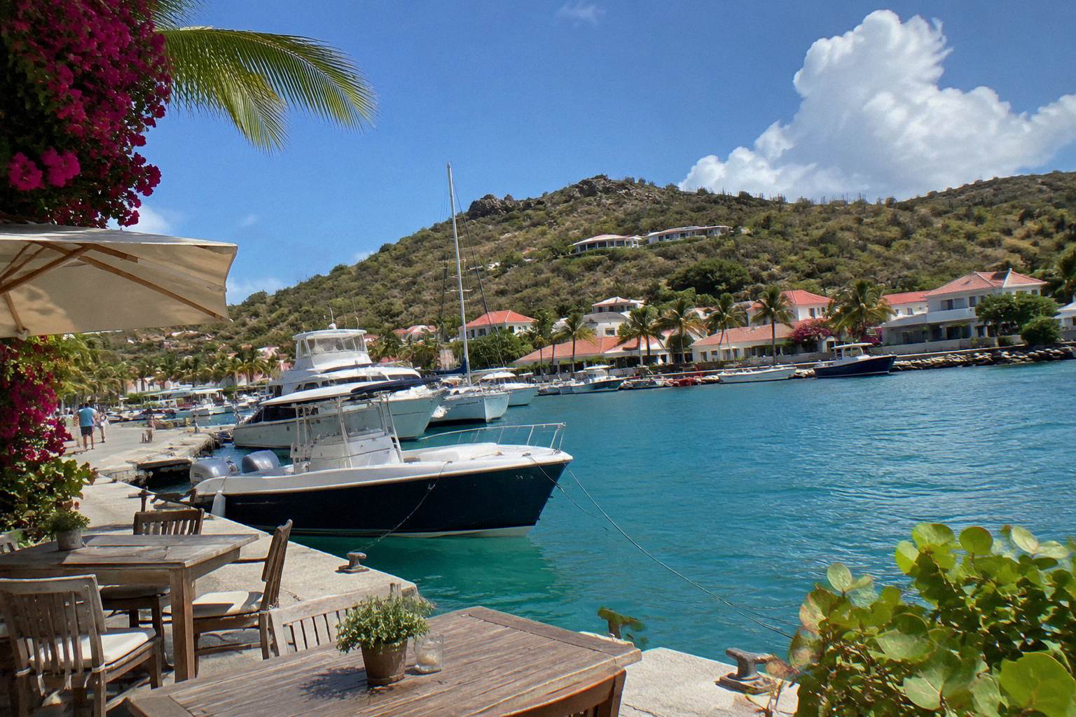 Harbourfront terrace tables beside moored boats at dusk in Gustavia