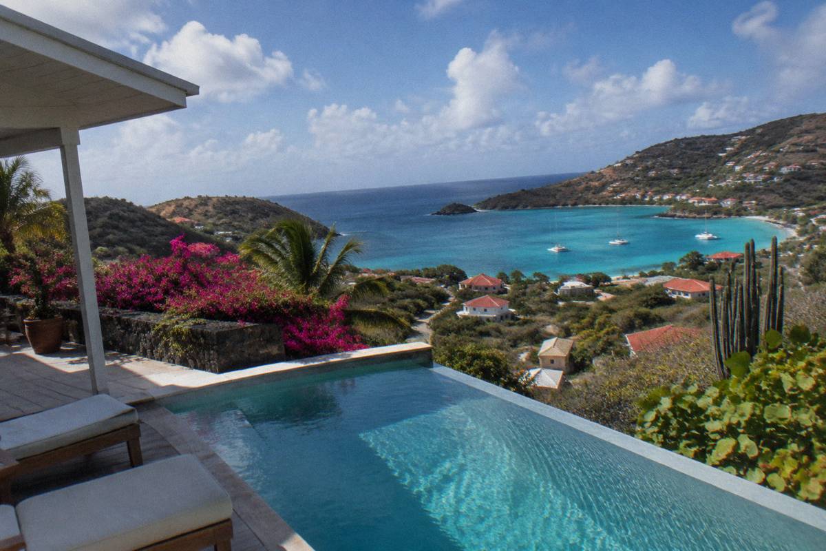 Modern villa with an open terrace and pool facing the sea between hills